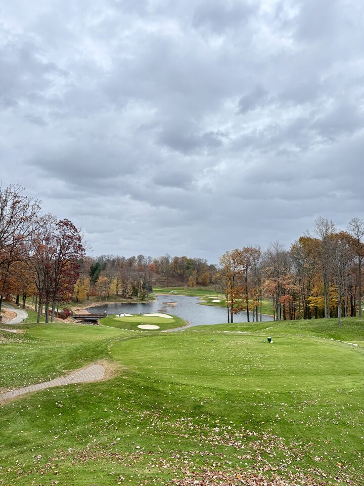 A pond and bunkers ringed by trees in fall color